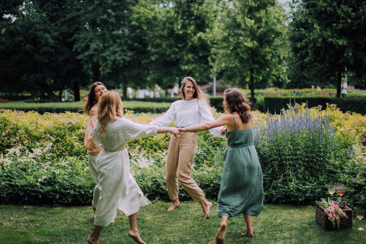 A group of women joyfully dancing in a park on a summer day, exuding happiness.